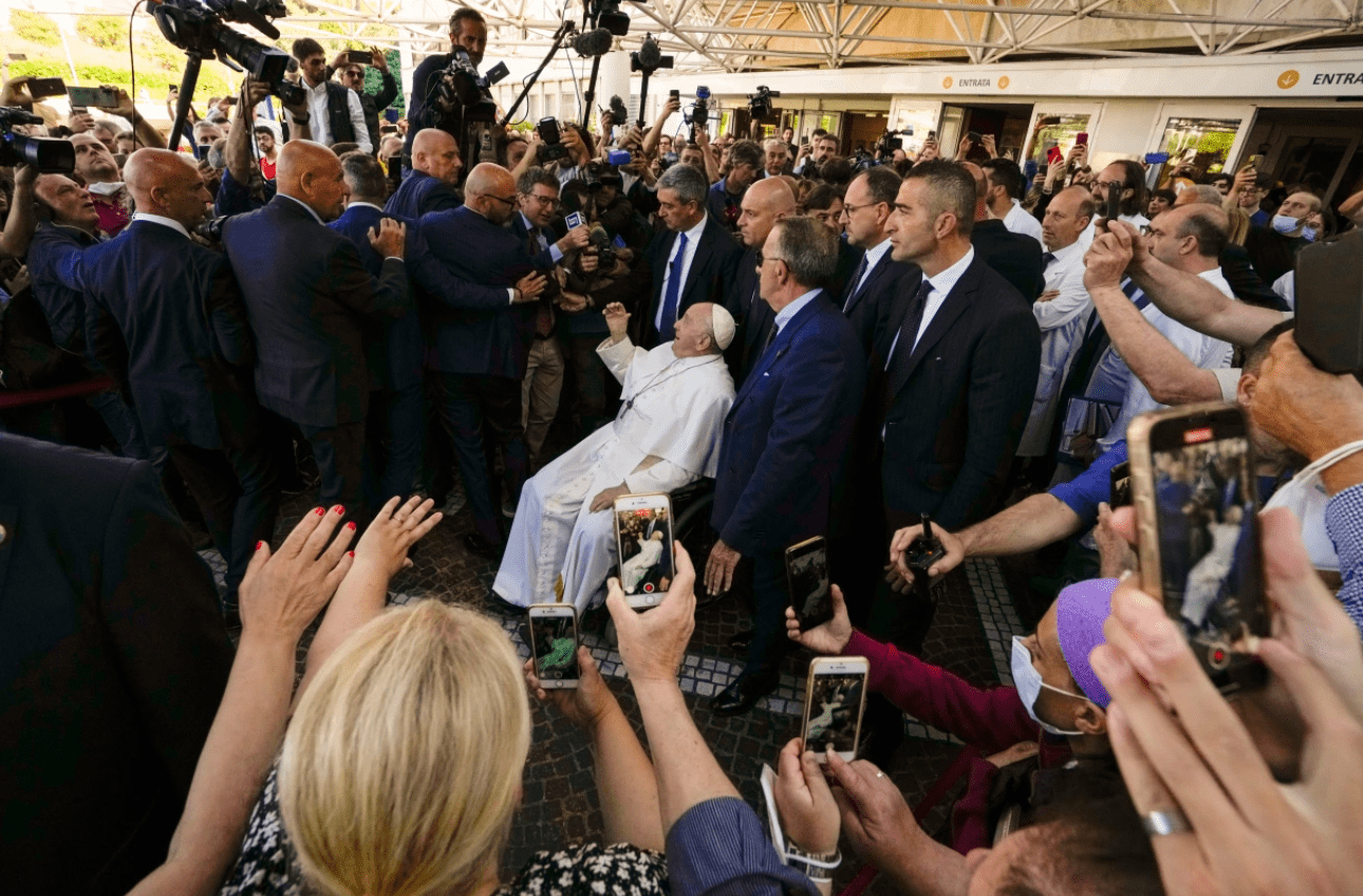 Pope Francis, 86, waves and smiles as he exits the hospital following a hernia operation in a wheelchair.